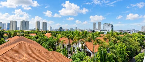 Zona residencial con tejados rojos, abundante vegetación y edificios altos al fondo.