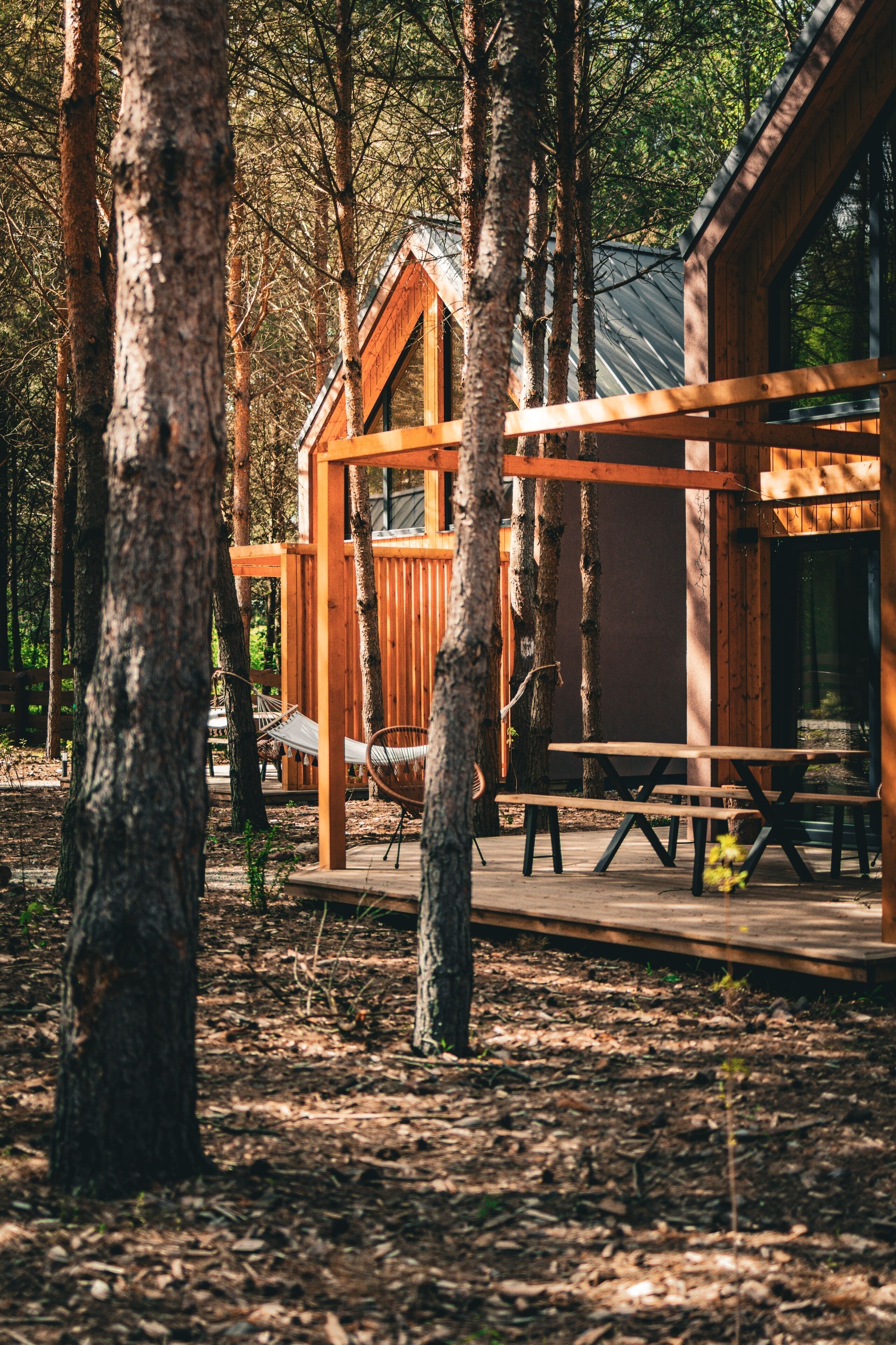 Een chalet met een houten terras, omgeven door bomen.