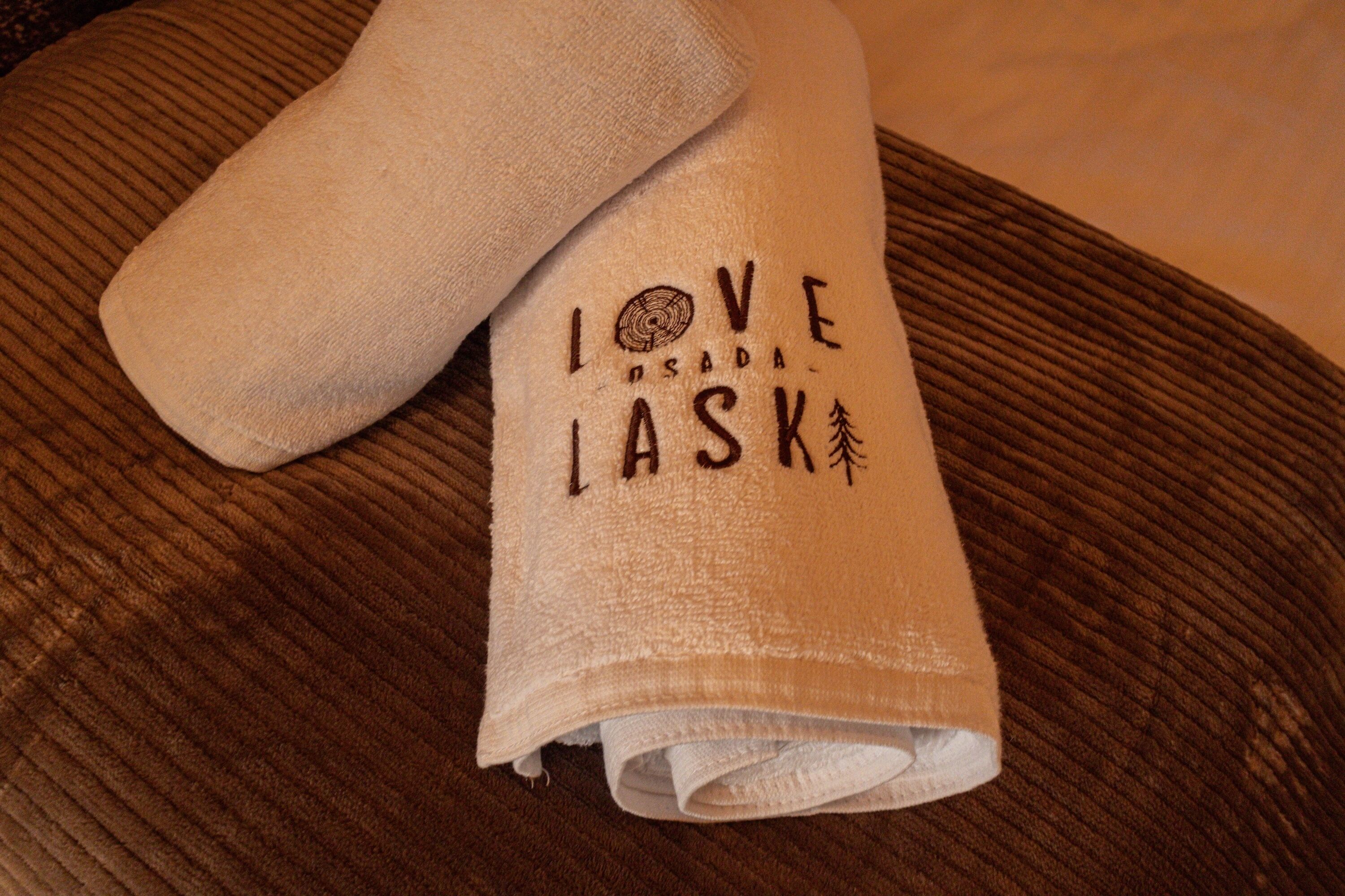 Ein gefaltetes Handtuch mit dem Aufdruck "LOVE ISADA LASK" und einem Kiefernbaum-Symbol.