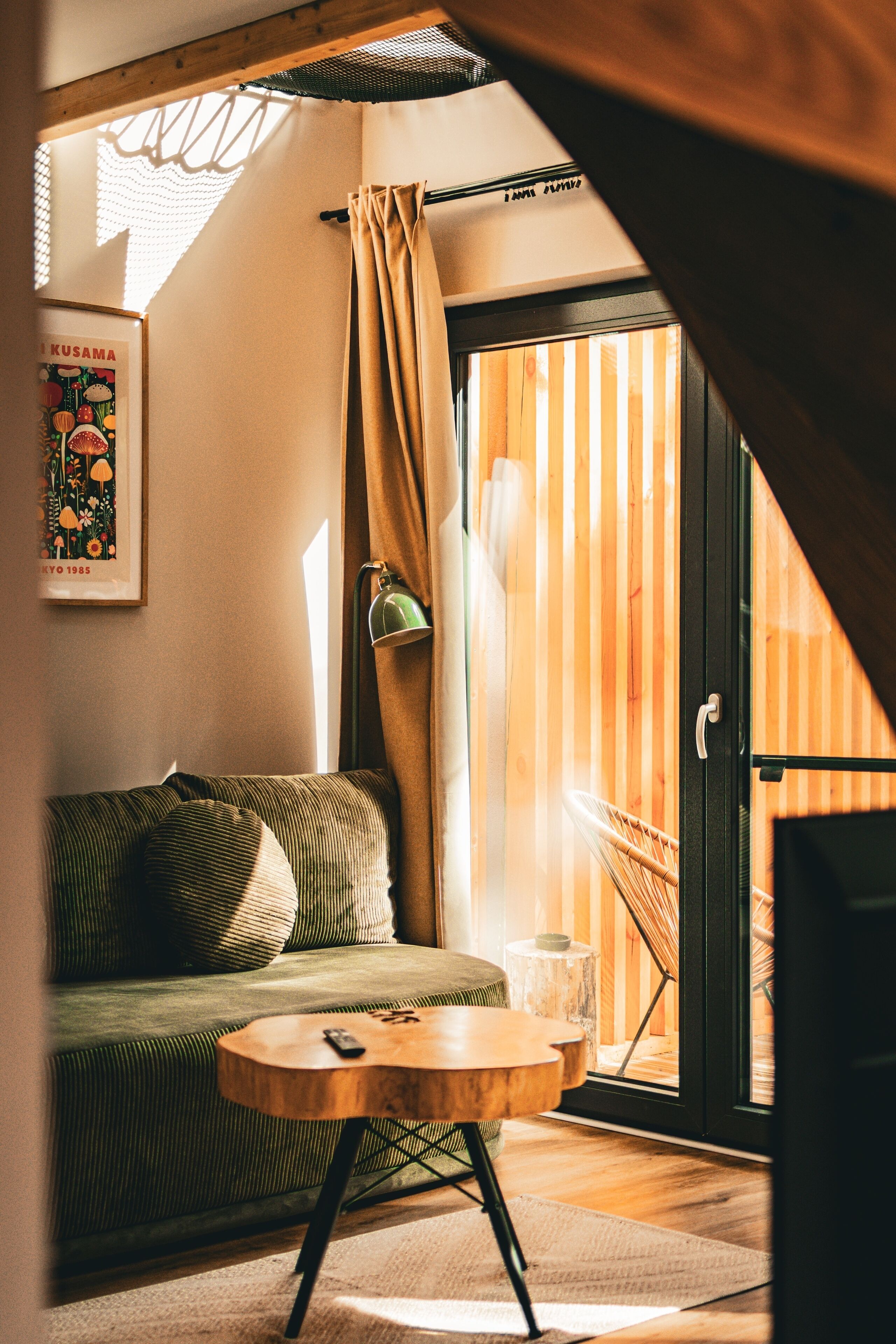 A cozy room with a green sofa, a small wooden table, and a view of a wooden deck through a sliding door.