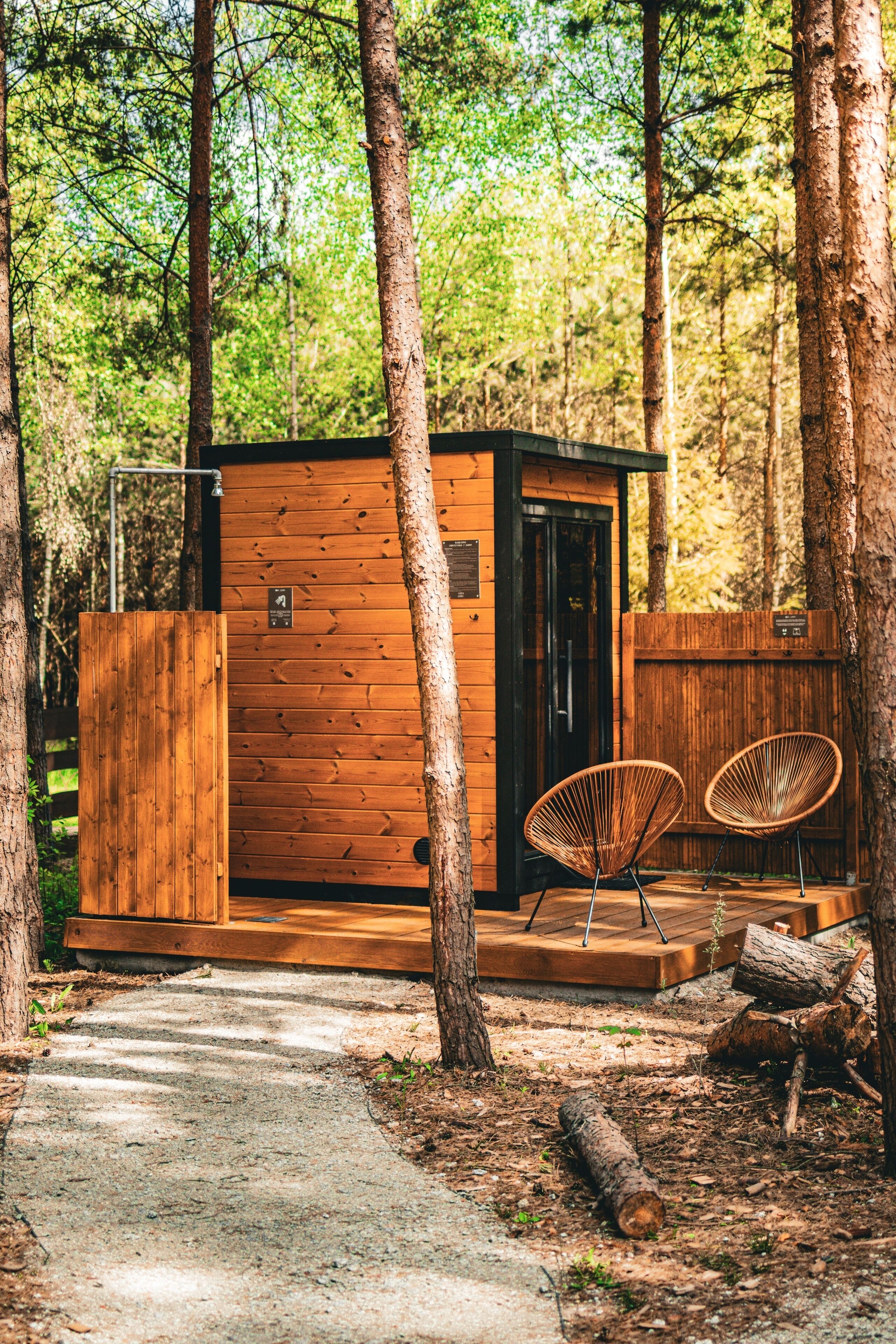 A wooden cabin with a door, two wicker chairs, and a wooden deck.