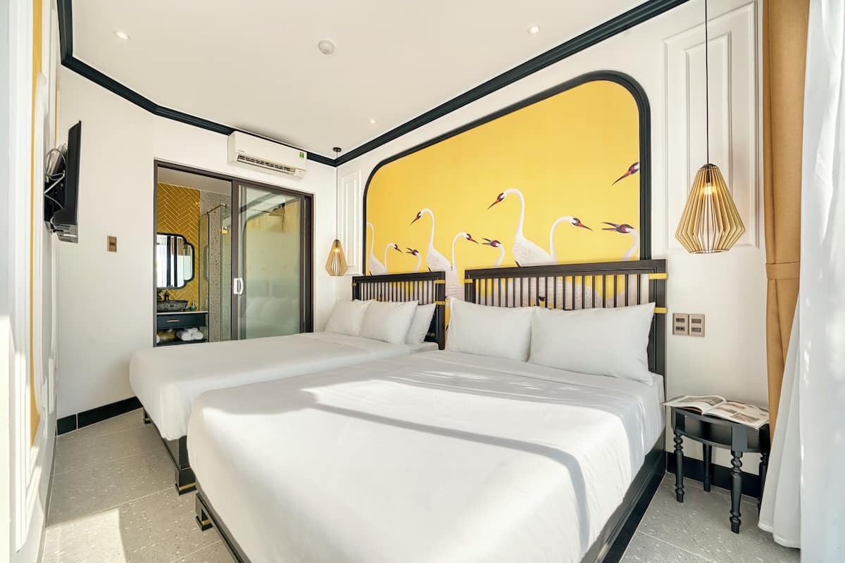 A hotel room with two beds, a large mirror, a vanity with a sink, and a wall mural of swans.