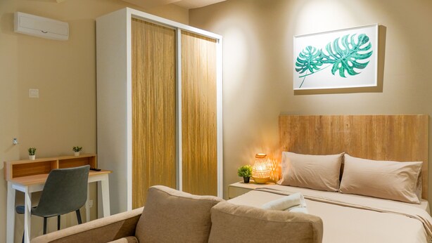 Una habitación de hotel con cama, escritorio, silla y mesita de noche con lámpara.