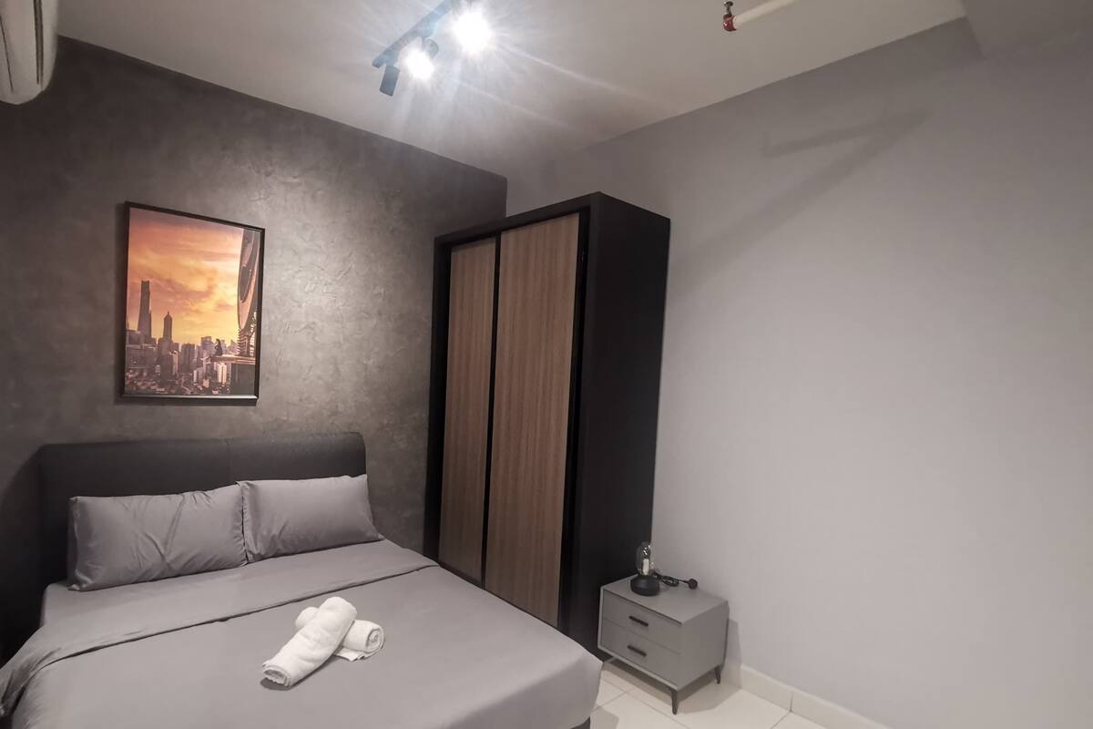 Quarto moderno com cama, mesa de cabeceira, guarda-roupa e pintura de paisagem urbana na parede.