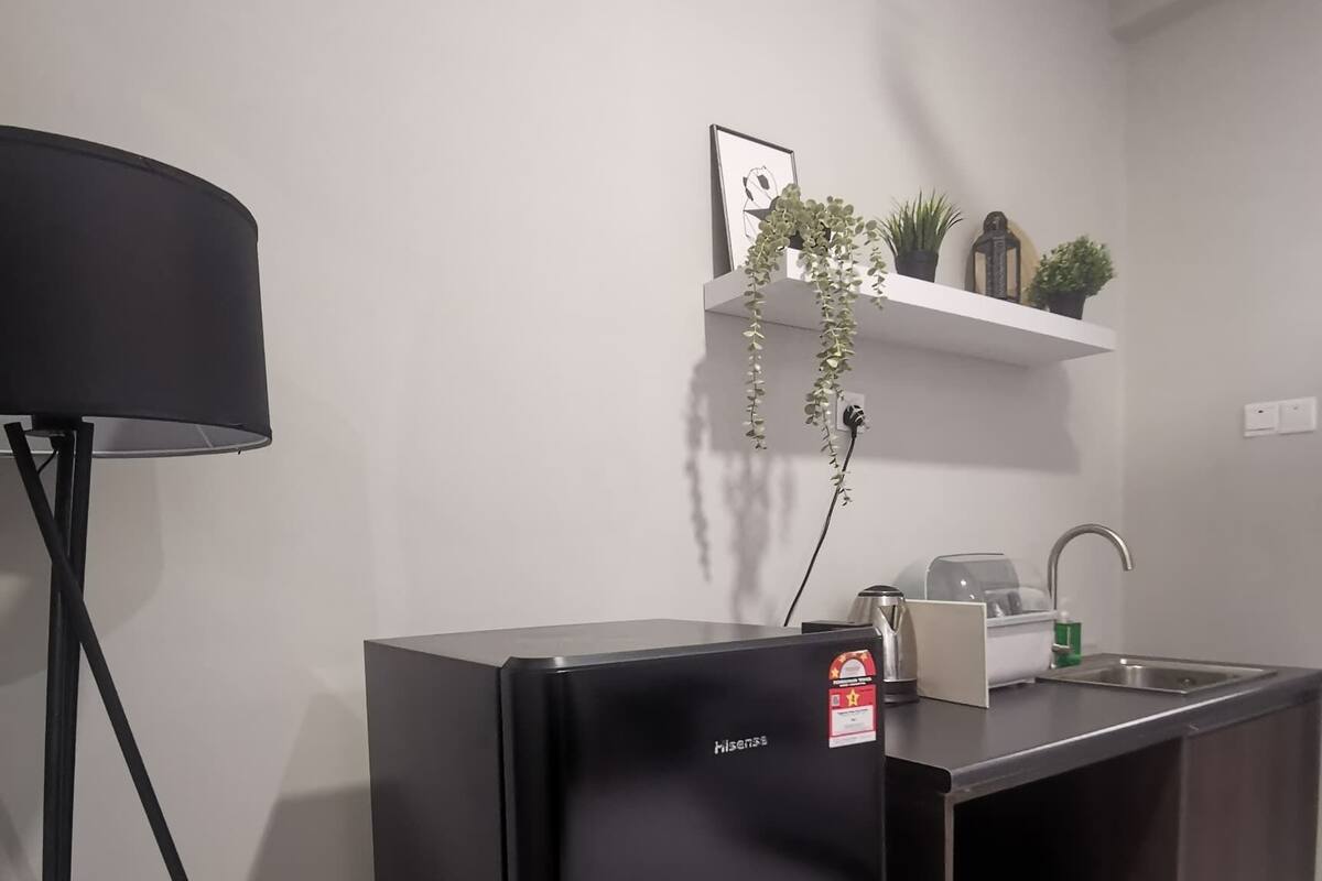 Cozinha moderna com geladeira preta, pia e bancada.
