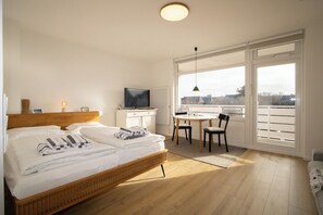 Un dormitorio con cama, televisión, escritorio y vistas a través de amplios ventanales.