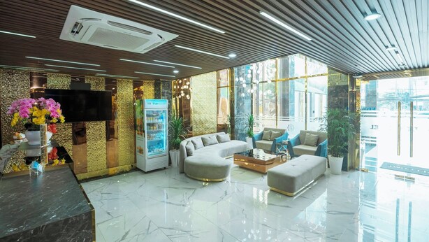 Un hall d’entrée moderne avec un sol en marbre, un espace détente avec des canapés, un distributeur automatique et une grande fenêtre donnant sur l’extérieur.