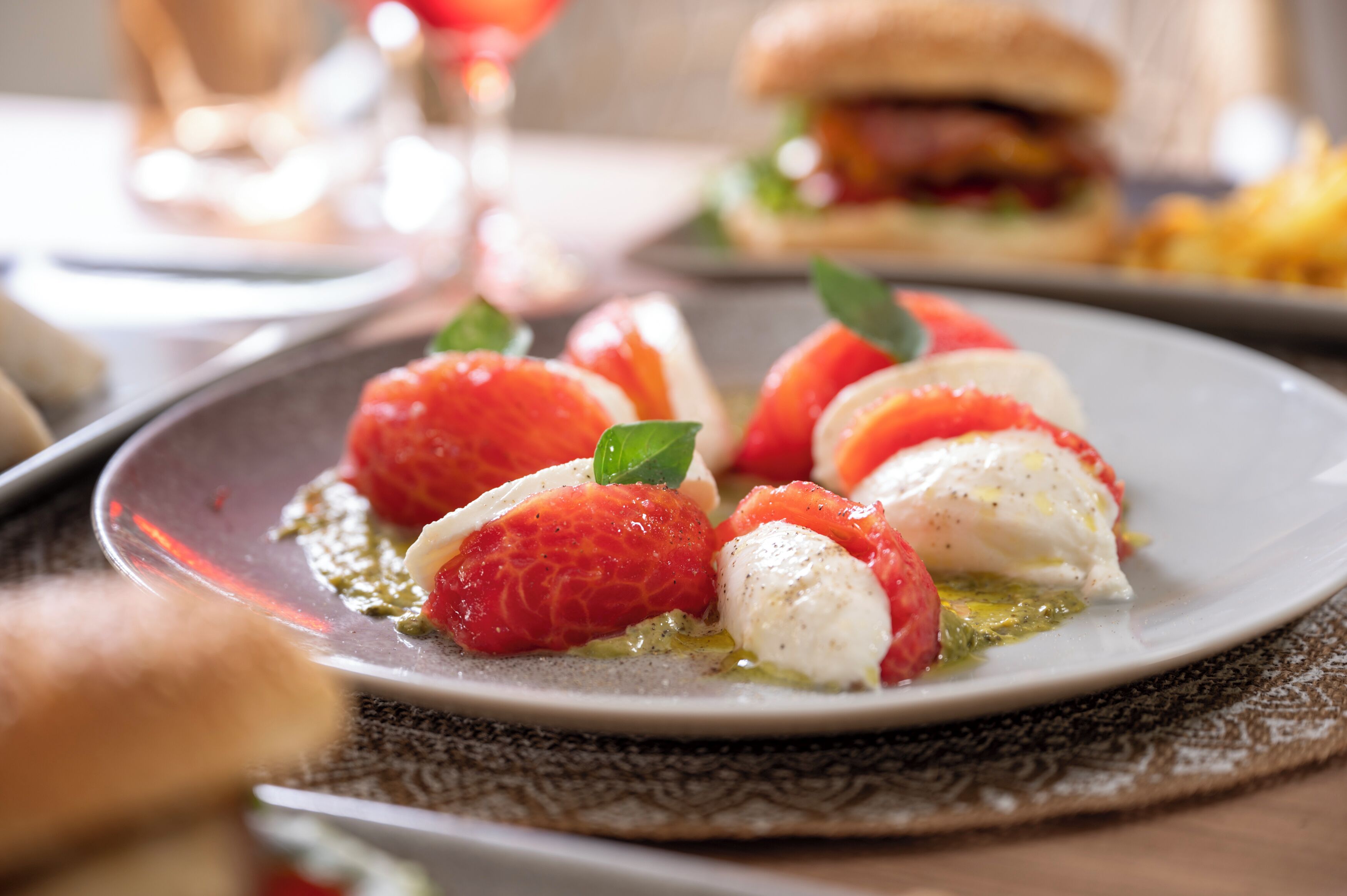 Lautasella on mozzarella-palloja ja tomaatteja, mahdollisesti Caprese-salaatti, ja lautasliina on kuvioitu.