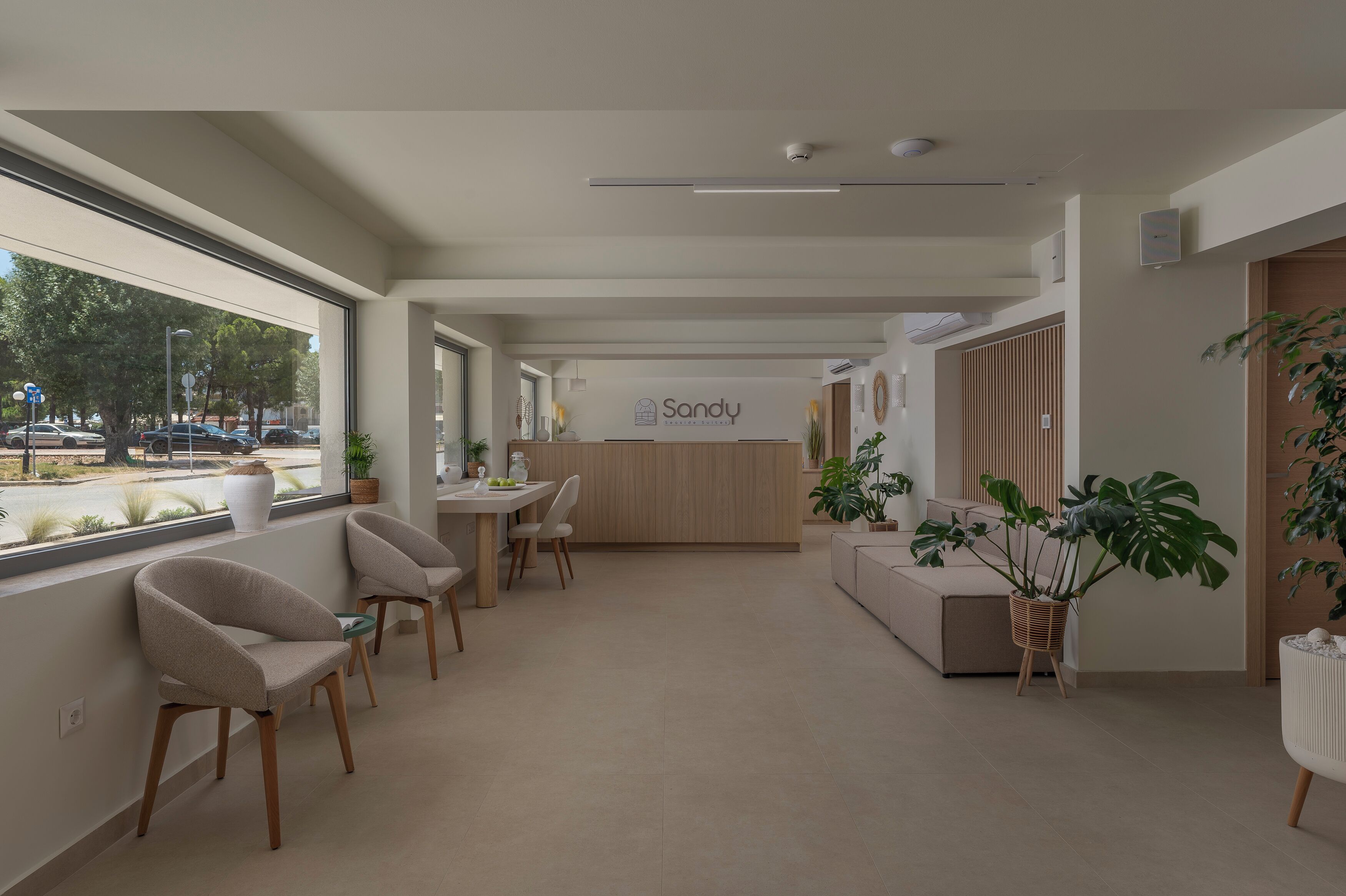 Un área de recepción moderna con mostrador, zona de estar y amplios ventanales con vistas a la calle.