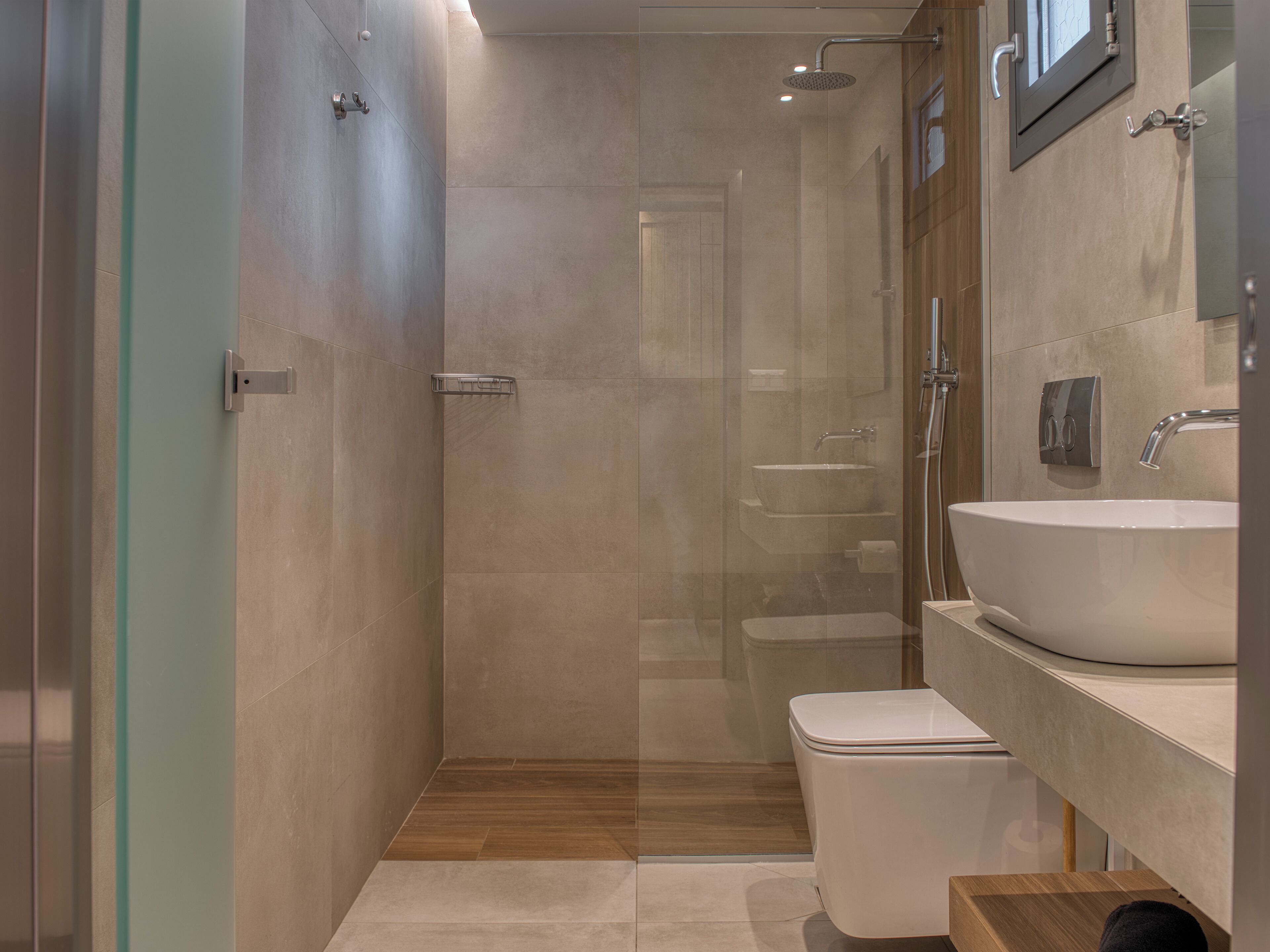 A modern bathroom with a glass shower enclosure, a white sink, and a toilet.