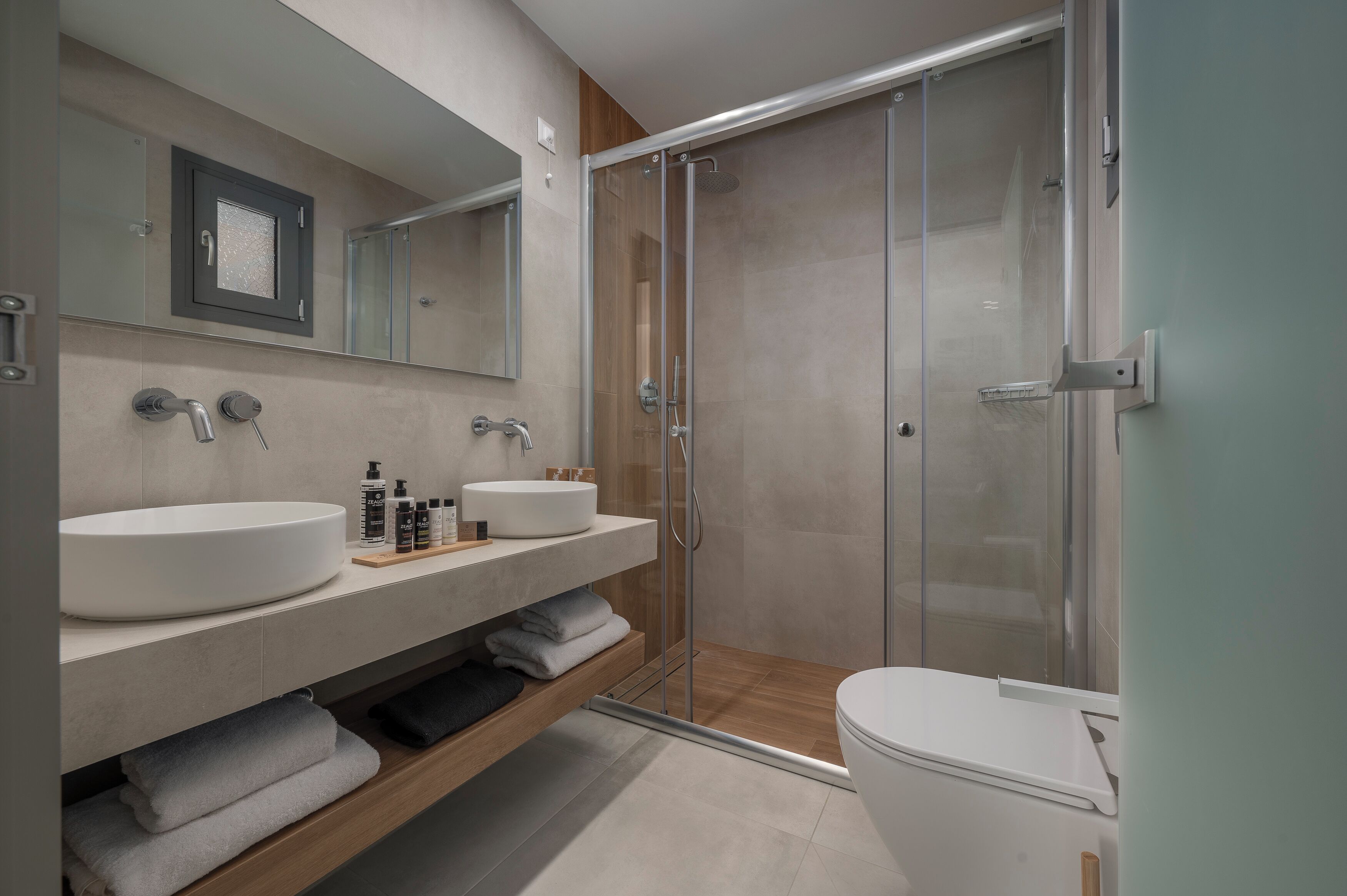 A modern bathroom with a glass-enclosed shower, a large sink, and a toilet.