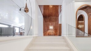 A modern interior with a staircase leading to a wooden ceiling and a glass railing. - Hotiday Room Collection - Napoli Diaz (Naples)