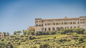 A large building with multiple arches and a tower, surrounded by greenery. - Hotiday Room Collection - Napoli Diaz (Naples)