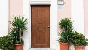 A wooden door with a circular emblem, flanked by two potted plants. - 3975 Il Feudo - Suite Decò by Barbarhouse (Bari)