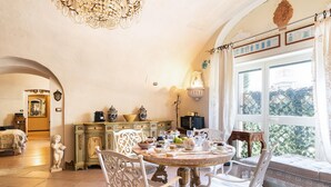 A dining area with a round table, white chairs, and a chandelier. - 3975 Il Feudo - Suite Decò by Barbarhouse (Bari)