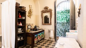 Una cocina con piso a cuadros, una mesa blanca y un mueble con adornos.