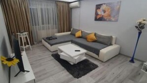 A modern living room with a sofa, coffee table, and a painting on the wall. - Lovely Urban Retreat (București)