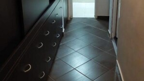 A hallway with a tiled floor and a door leading to a room with a shower. - Lovely Urban Retreat (București)