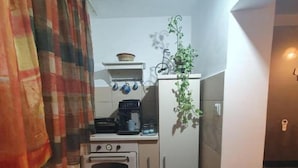 A compact kitchen with a stove, oven, and a refrigerator. - Lovely Urban Retreat (București)