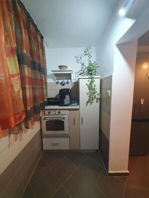 A compact kitchen with a stove, oven, and a refrigerator. - Lovely Urban Retreat (București)