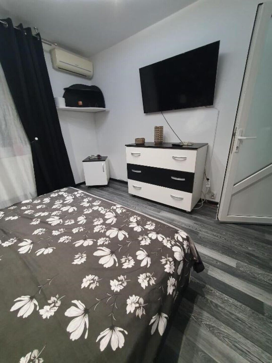 Een slaapkamer met een bed, een dressoir, een televisie en een airconditioning.