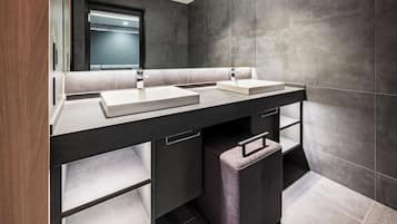 A modern bathroom with two sinks, a mirror, and built-in storage.