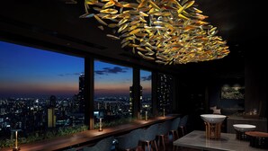A modern bar area with a city view, large windows, and contemporary lighting fixtures.