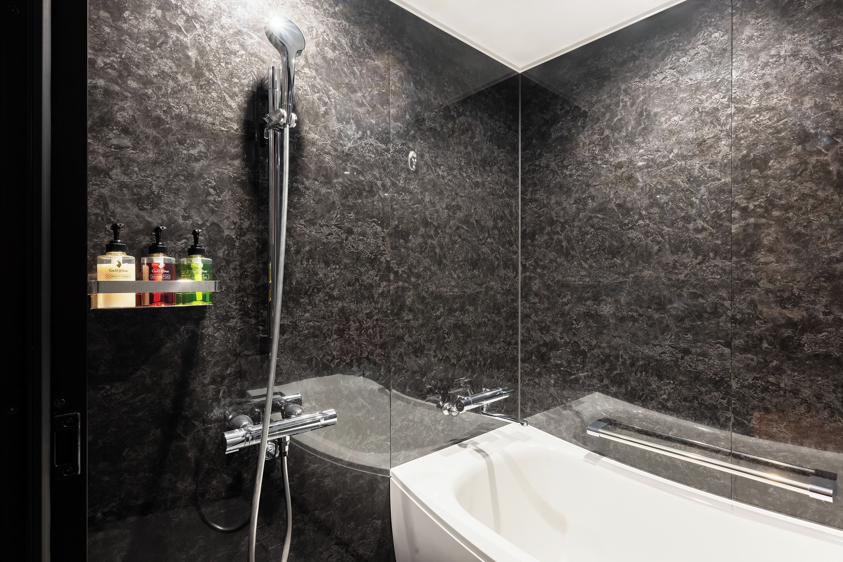 Une salle de bain moderne avec une douche à parois de verre, une baignoire blanche et un mur en marbre.