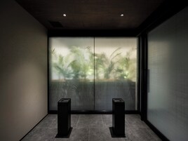 Habitación moderna con puerta de vidrio corredera, dos altavoces negros y una pared con textura.