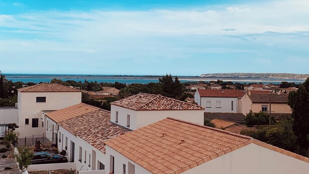 A coastal residential area with terracotta-tiled roofs, white walls, and a view of the sea. - Modern family home, close to beaches and garrigue (La Palme)