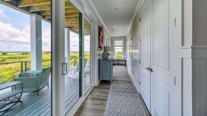 En korridor med utsikt över det fria, en inglasad veranda med sittplatser och en hall som leder till en dörr.