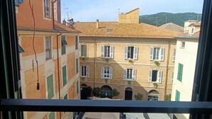 A view from a balcony overlooking a courtyard with buildings, a clear sky, and a mountain in the background. - Delle Erbe The Nightlife (Albenga)