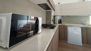A modern kitchen with a built-in microwave, gas stove, coffee maker, and dishwasher. - Delle Erbe The Nightlife (Albenga)