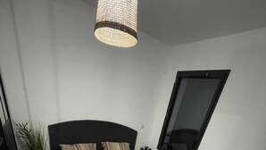 Ein Schlafzimmer mit einem Bett, einem Blumentopf, einem kleinen runden Tisch und einem an der Wand befestigten Fernseher.