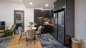 Une cuisine moderne avec des meubles de couleur sombre, un plan de travail en marbre et un réfrigérateur encastré.