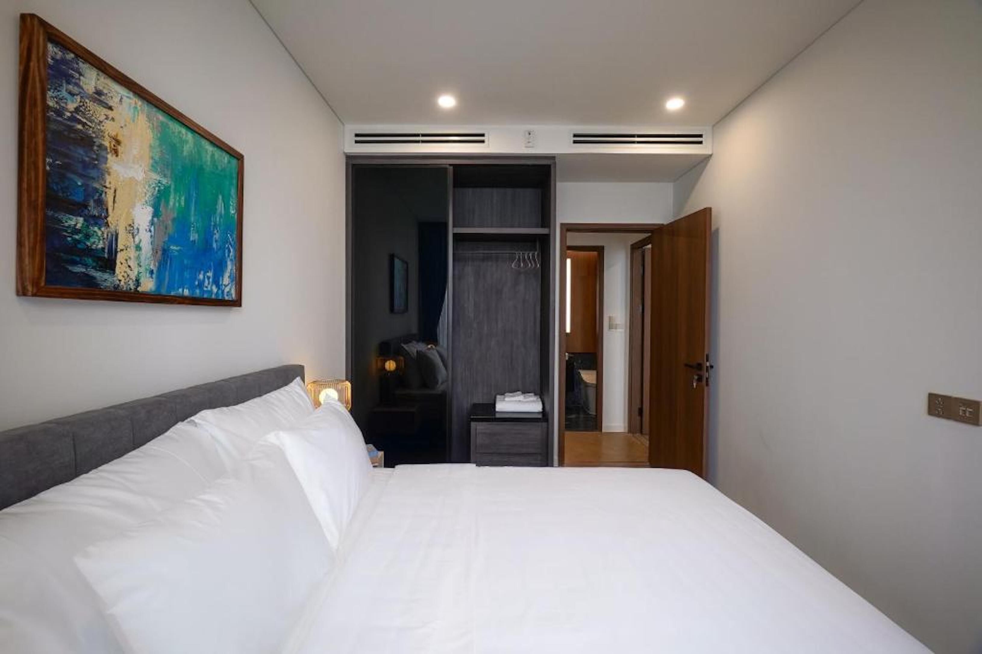 Une chambre d’hôtel moderne avec un grand lit, une armoire et un tableau au mur.