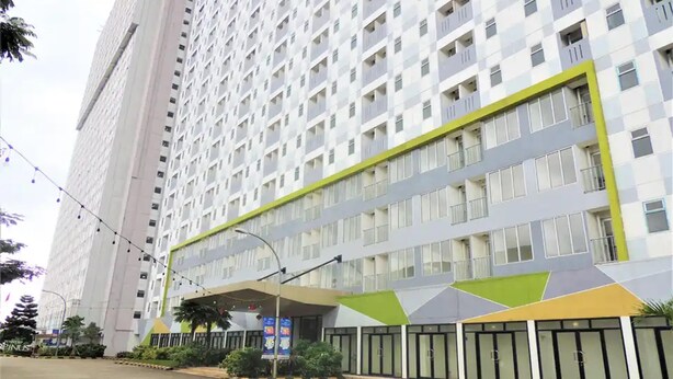 Een hotel met meerdere verdiepingen en een modern gevelontwerp, met een geometrisch patroon en een opvallend groene accentkleur.