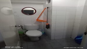 Een kleine, praktische badkamer met toilet, bidet en spiegel.