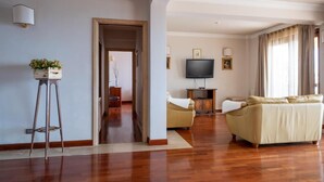 A spacious living room with a wooden floor, a beige sofa, a television, and a small table with a plant. - Villa La Gorgone - Sea View (Taormina)