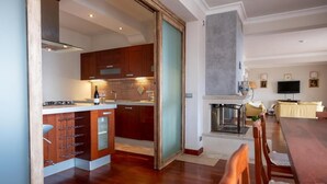 A modern kitchen with wooden cabinets, a dining area with a wooden table and chairs, and a living room with a sofa and a television. - Villa La Gorgone - Sea View (Taormina)