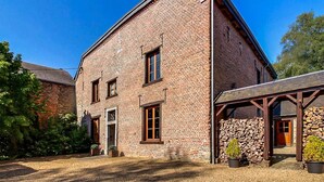 A two-story brick building with a gabled roof, a stone foundation, and a covered porch with wooden beams. - Amazing home in Gedinne with sauna (Gedinne)