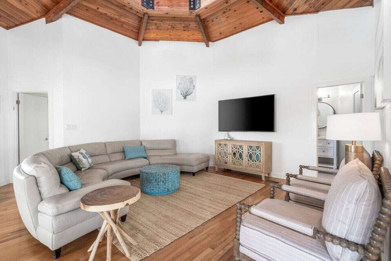 A living room with a sectional sofa, a round coffee table, a cabinet, a TV, and a chair.