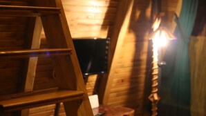 A wooden ladder in a room with sloped ceilings and a fireplace. - Pagen Bungalov (Hopa)