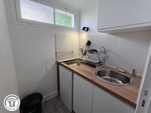 Enjoy cooking in this well-lit kitchen with a dish rack and small refrigerator.