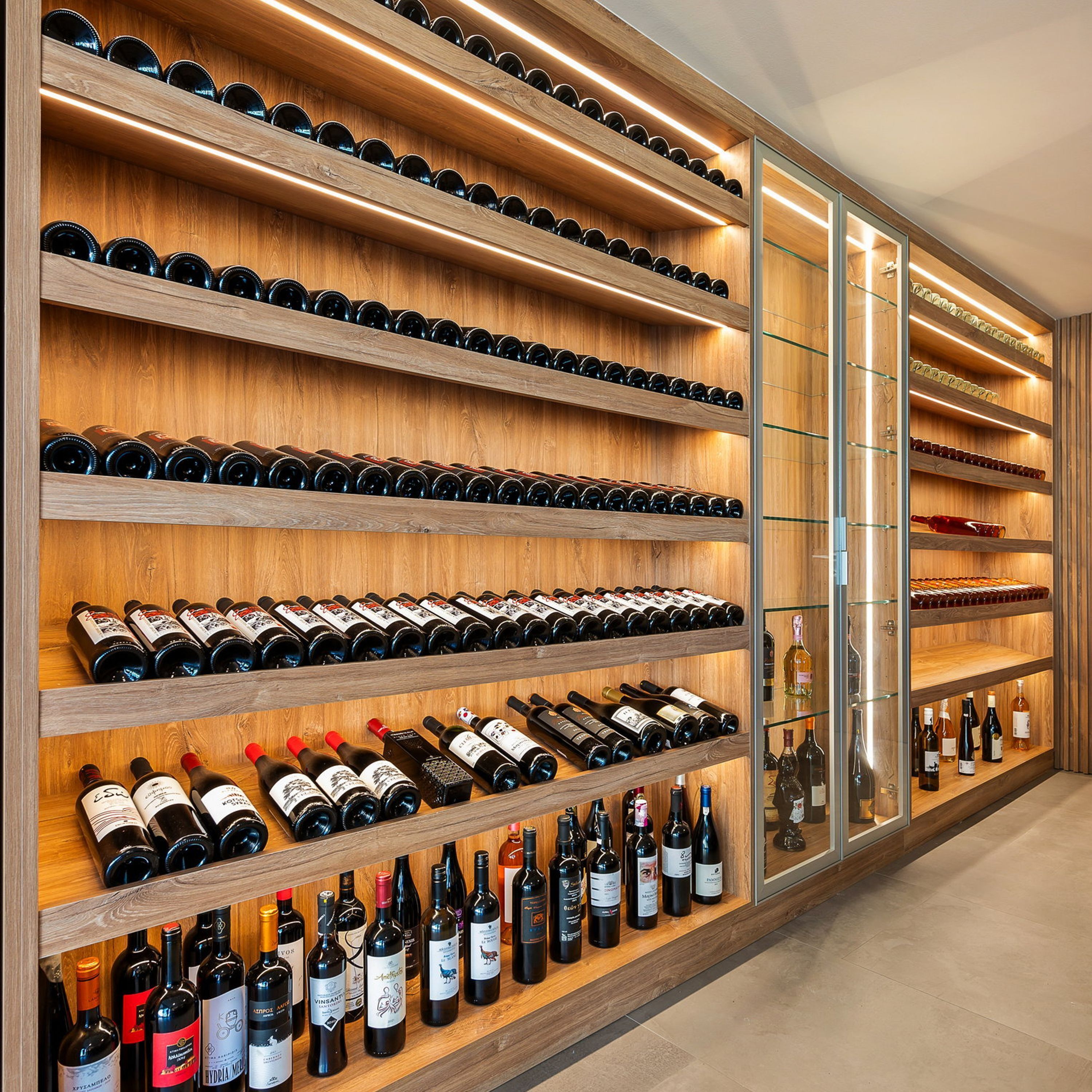 Una bodega con múltiples estantes de madera y vitrinas de vidrio, mostrando una variedad de botellas de vino.