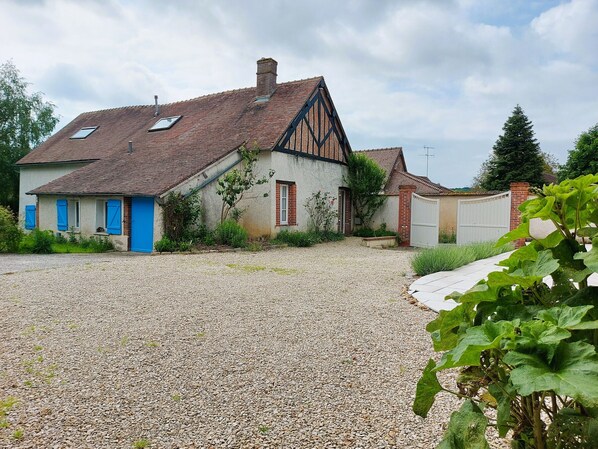 Une maison avec une allée en gravier, une porte bleue et un toit en pente.