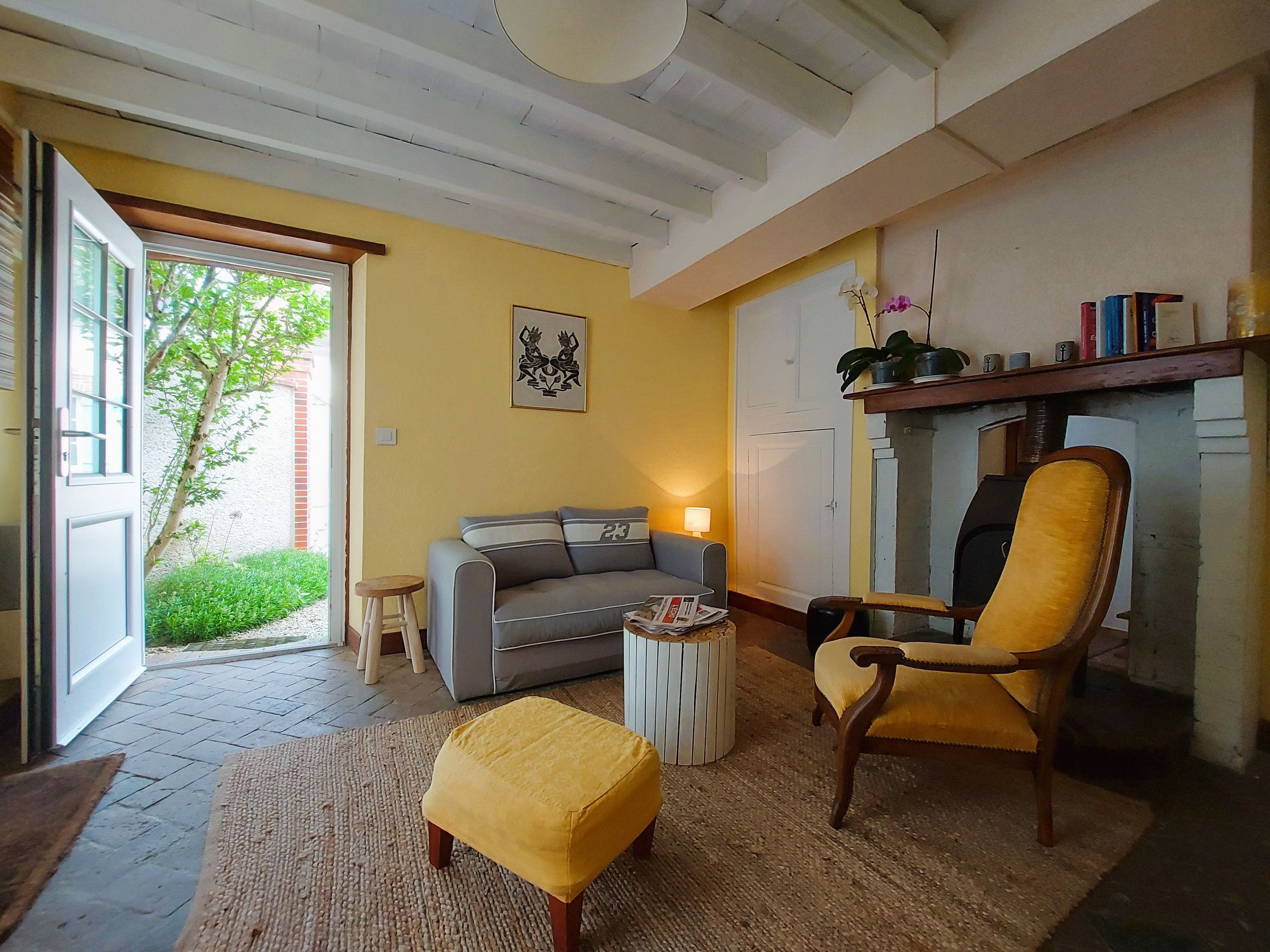 A living room with a sofa, armchair, ottoman, and a fireplace.
