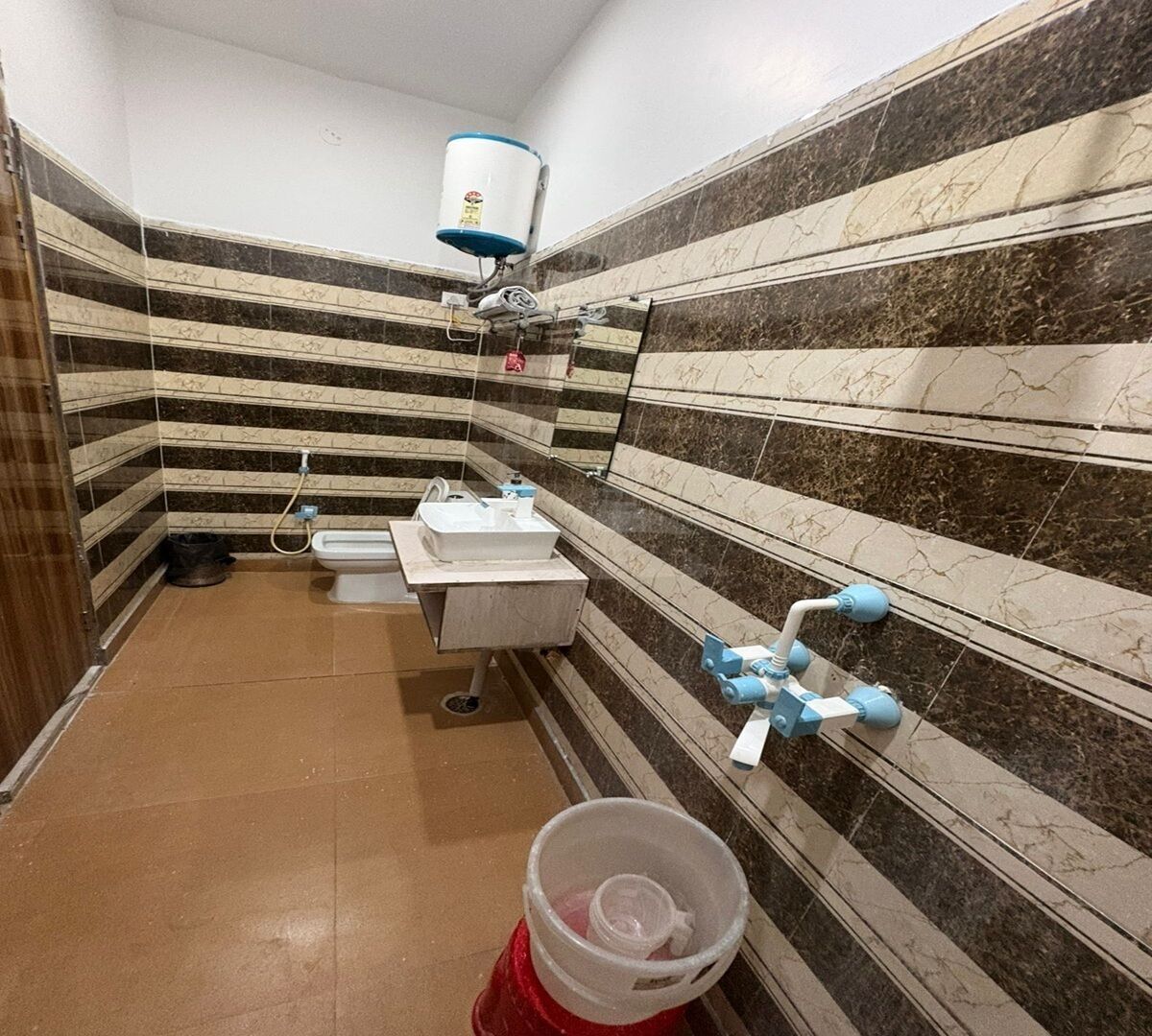 Une petite salle de bain comprenant des toilettes, un lavabo et un chauffe-eau fixé au mur.