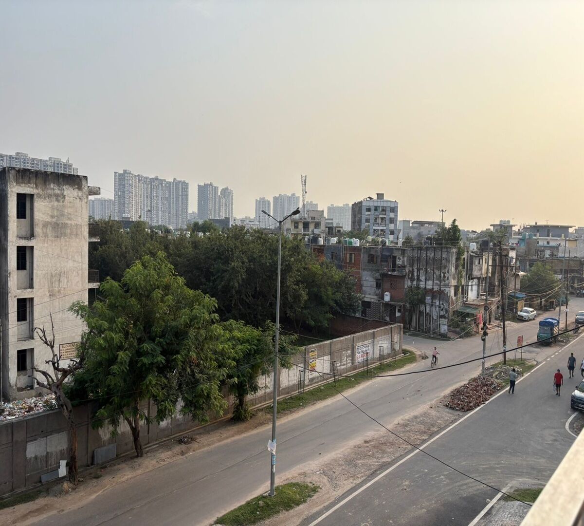 A cityscape with high-rise buildings, a road with pedestrians, and a tree-lined sidewalk.