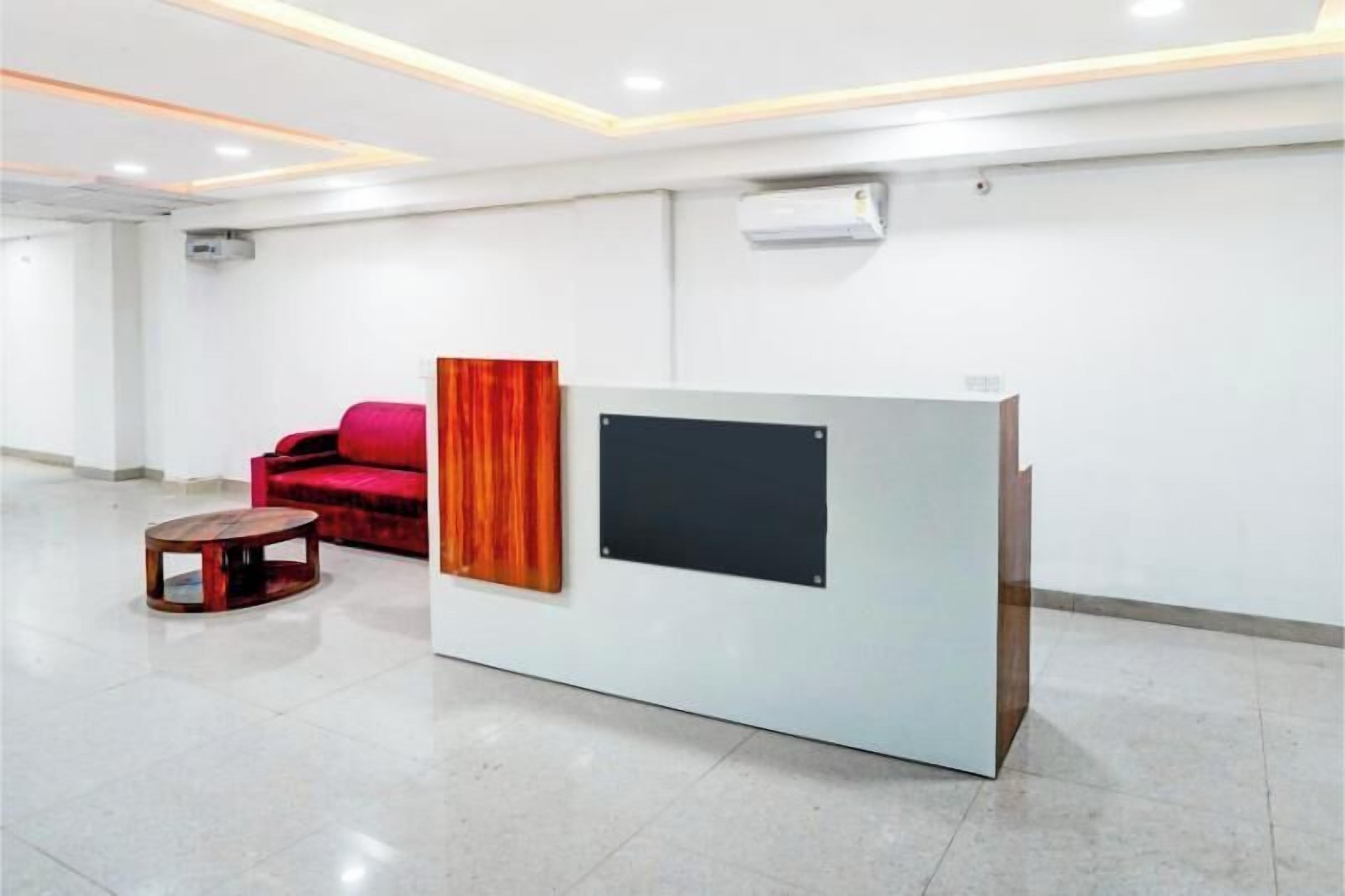 A reception area with a modern desk, a red sofa, and a small round table.